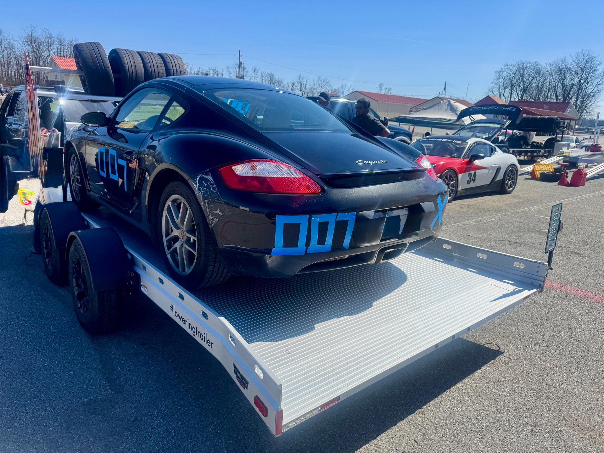 Our black Porsche Cayman, number 007, loaded on a trailer in the track paddock